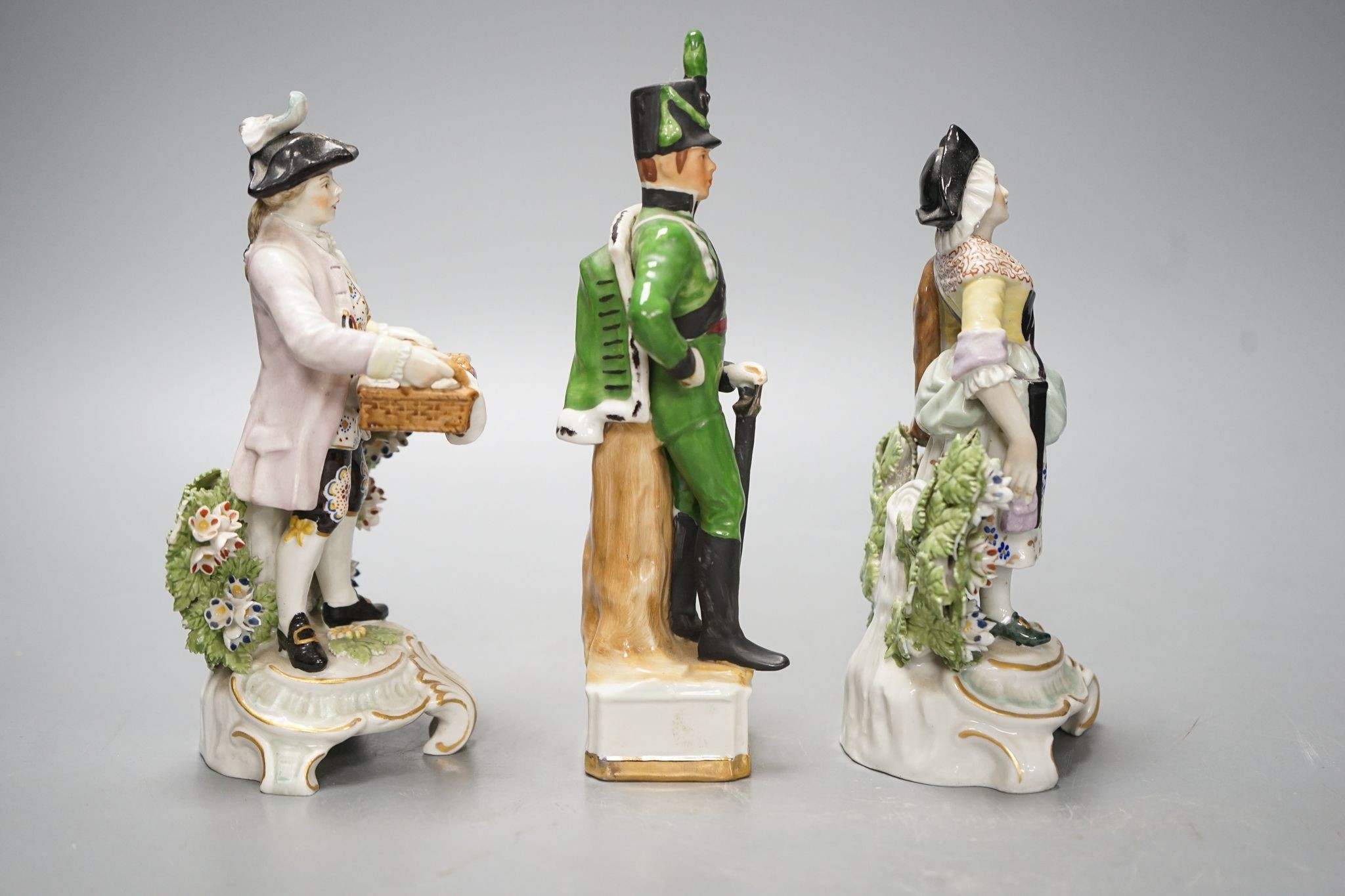A pair of Dresden porcelain figures of a street-trader and companion and a continental porcelain figure of a Rifle Brigade officer (3) 19.5cm